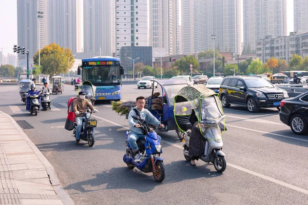 Pessoas em bicicleta elétrica com pára-brisas colorido na encruzilhada, Hefei, China. — Fotografia de Stock