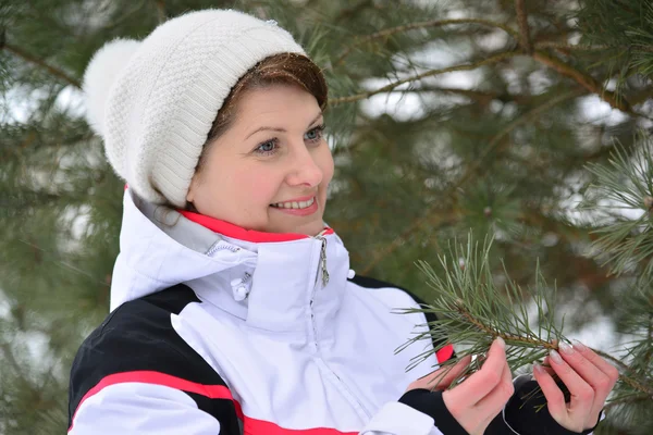 Mulher em jaqueta esportiva e chapéu na floresta de pinheiros de inverno — Fotografia de Stock