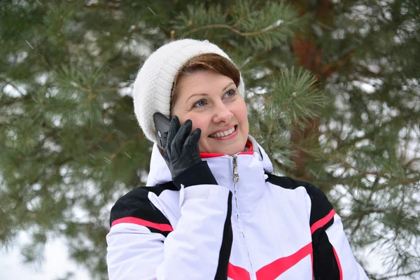 Sport vrouw praten over telefoon in winter dennenbos — Stockfoto