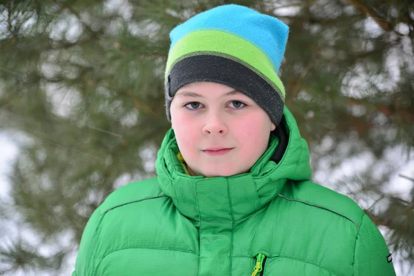 Pojke tonåring i grön jacka på vintern tallskog — Stockfoto