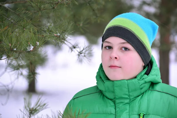 Niño adolescente en chaqueta verde en el bosque de pinos de invierno — Foto de Stock