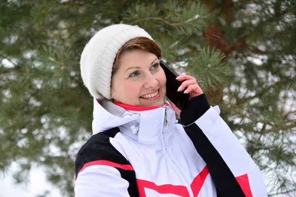 Sport woman talking on phone in  pine winter forest — Stock Photo, Image