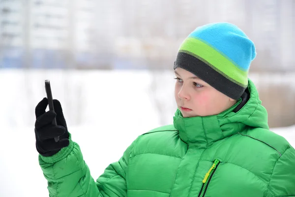 Menino adolescente com telefone celular ao ar livre no inverno — Fotografia de Stock