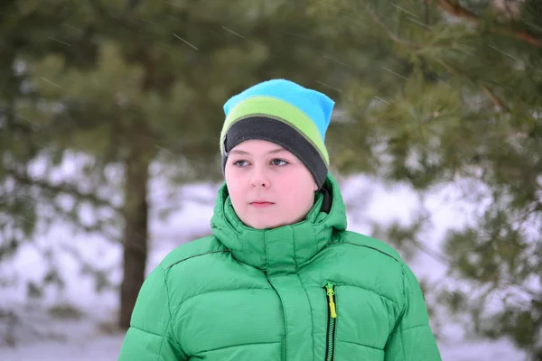 Jugendlicher in grüner Jacke im winterlichen Kiefernwald — Stockfoto