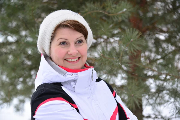 Frau in Sportjacke und Hut im winterlichen Kiefernwald — Stockfoto