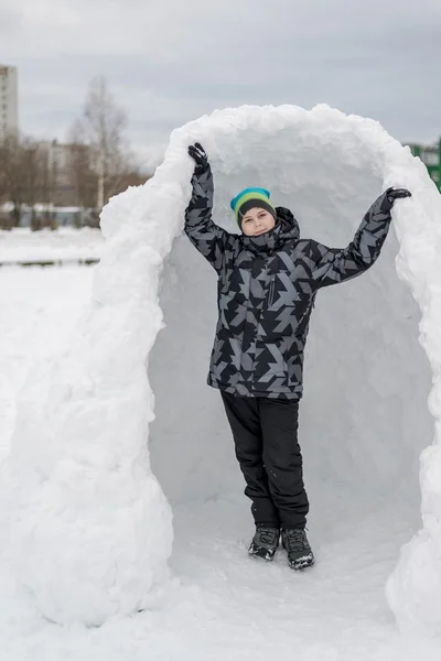 その場しのぎの雪の砦に立っている十代の少年 — ストック写真