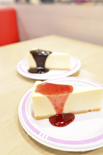 Tarta de queso bajo salsa de fresa en una tabla de cortar blanca —  Fotos de Stock