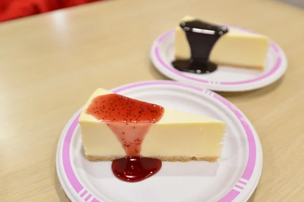 Cheesecake bir beyaz kesme tahtası üzerinde çilek sosu altında — Stok fotoğraf