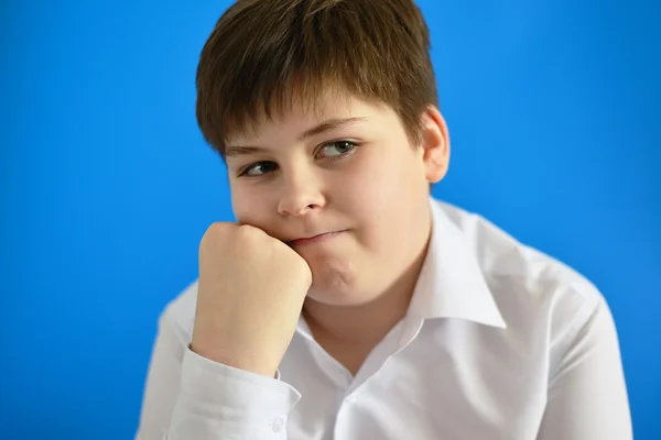 Fundersam tonårspojke på blå bakgrund — Stockfoto