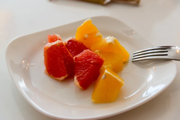 Кусочки апельсина и грейпфрута на тарелке — стоковое фото