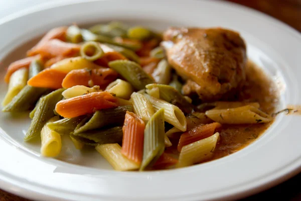 Colored pasta with chicken on plate — Stock Photo, Image