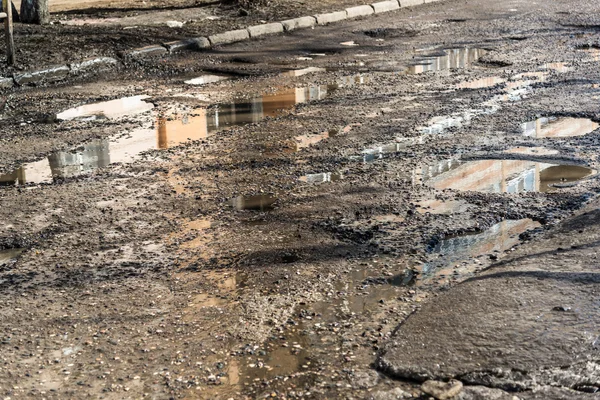 Ямы на асфальтированной дороге, заполненные водой — стоковое фото