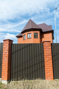 Yüksek bir çit arkasında kırmızı tuğladan Cottage