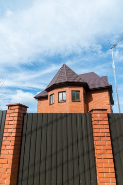 Yüksek bir çit arkasında kırmızı tuğladan Cottage