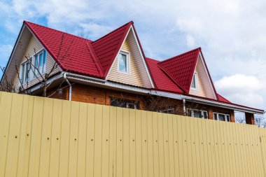 Yüksek bir çit arkasında kırmızı tuğladan Cottage