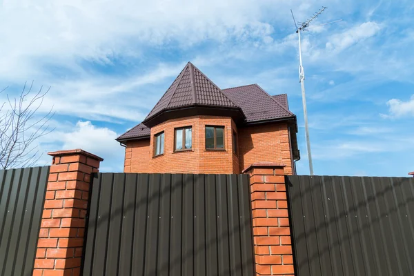 Domek z czerwonej cegły za wysokim ogrodzeniem — Zdjęcie stockowe