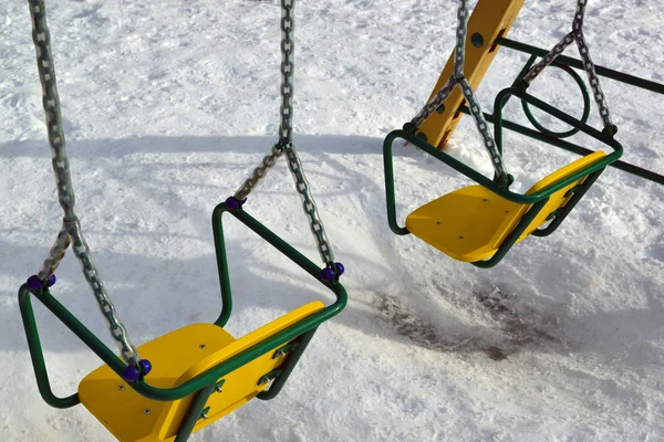 Качели на детской площадке зимой — стоковое фото