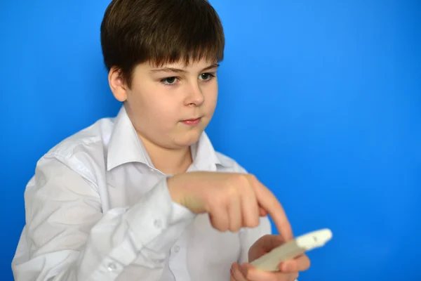 Niño adolescente con TV control remoto sobre un fondo azul — Foto de Stock