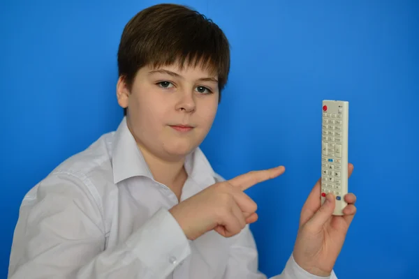 Niño adolescente con TV control remoto sobre un fondo azul — Foto de Stock