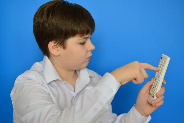 Niño adolescente con TV control remoto sobre un fondo azul — Foto de Stock