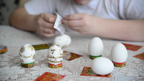 Мальчик клеит наклейки на пасхальные яйца — стоковое видео