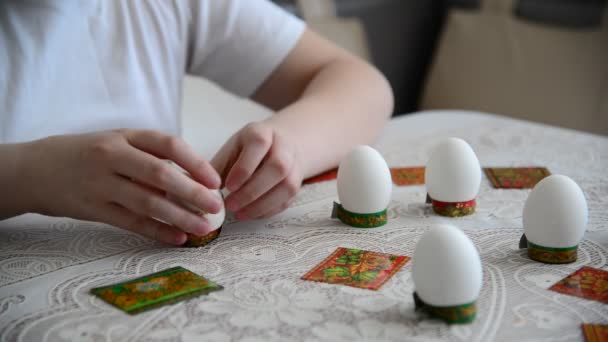 Мальчик клеит наклейки на пасхальные яйца — стоковое видео