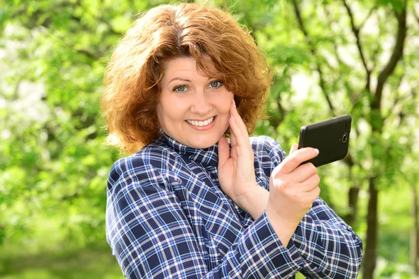 Жінка використовує мобільний телефон в парку — стокове фото