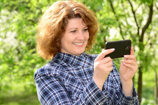 Woman using cell phone in park — Stock Photo, Image