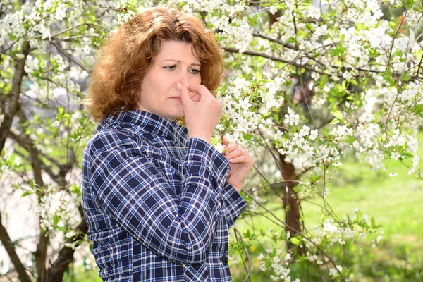 Donna che soffre di rinite allergica in un parco lussureggiante — Foto Stock