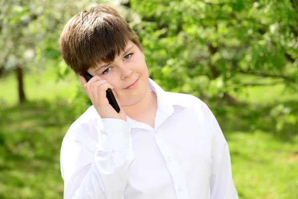 屋外の電話で話している十代の少年 — ストック写真