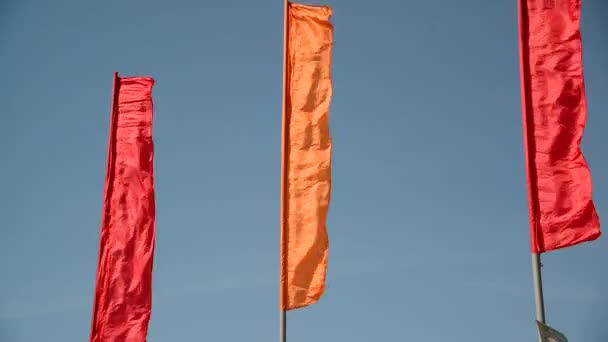 Banderas rojas y anaranjadas ondeando en el viento — Vídeo de stock