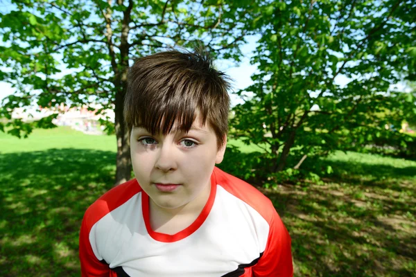 Funny teenager boy looks into camera in summer park — Stock Photo, Image