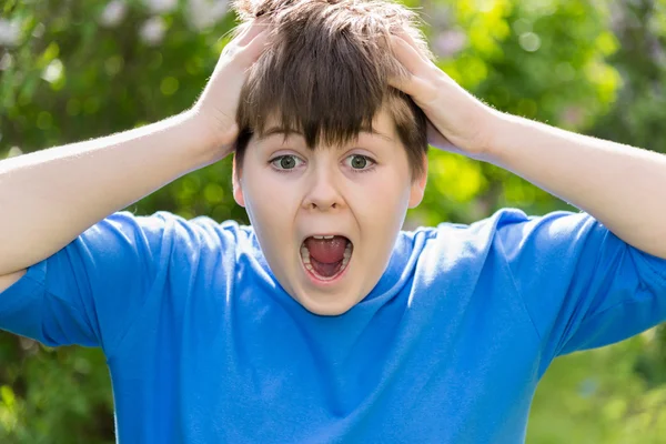 Adolescente chico gritando y cogido de la mano detrás de su cabeza — Foto de Stock