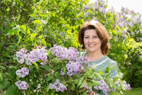 Vuxen kvinna i park nära den blommande Syren — Stockfoto