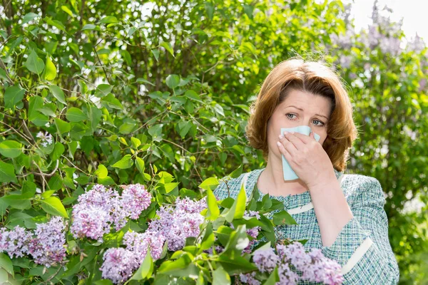 Woman suffering from pollen allergy about lilacs — Stock Photo, Image