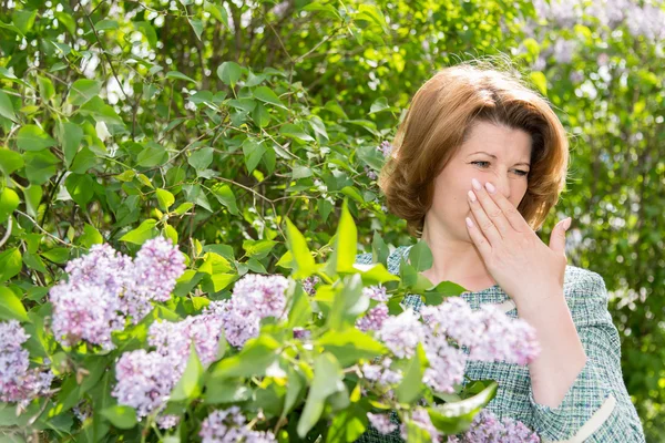 Woman suffering from pollen allergy about lilacs — Stock Photo, Image