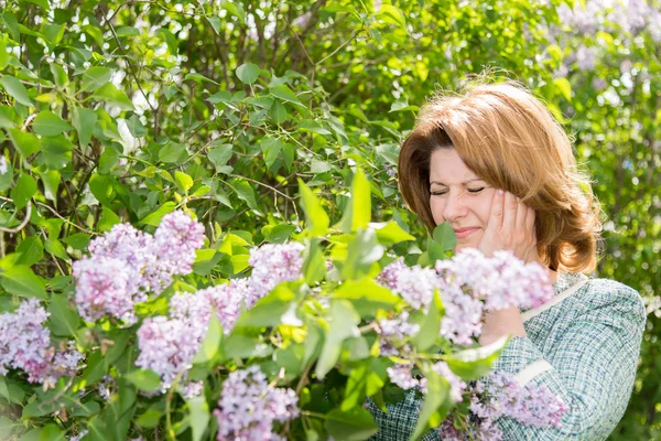 Mulher que sofre de enxaqueca sobre floração lilás — Fotografia de Stock