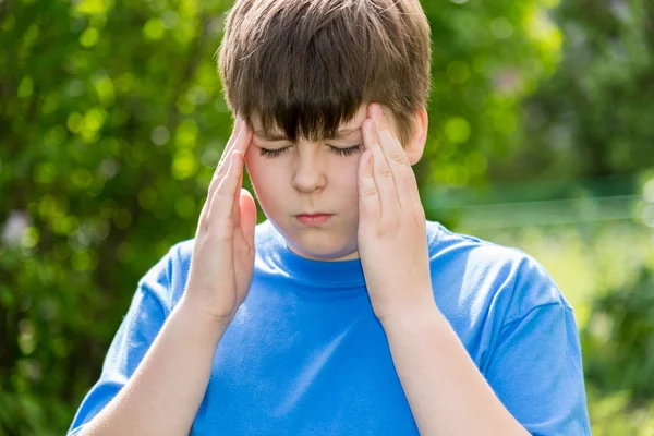 Boy teenager with headache on nature — Stock Photo, Image