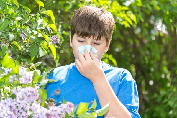 Ragazzo con rinite allergica vicino alla fioritura lilla — Foto Stock