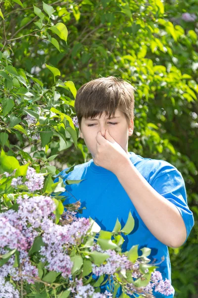 Ragazzo con rinite allergica vicino alla fioritura lilla — Foto Stock