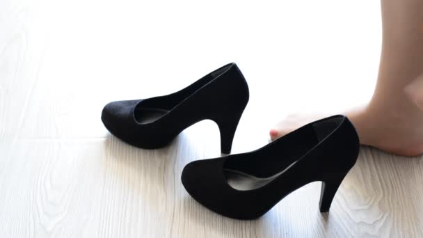 Vrouw zet op zijn voeten zwarte hoge hakken schoenen — Stockvideo