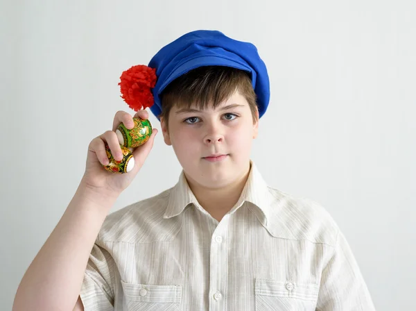 Menino em boné nacional russo com cravos segurando ovos de páscoa — Fotografia de Stock