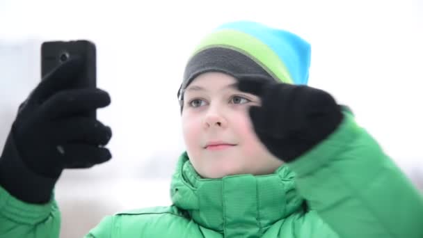 Menino usa celular com luvas touchscreen fora no inverno — Vídeo de Stock