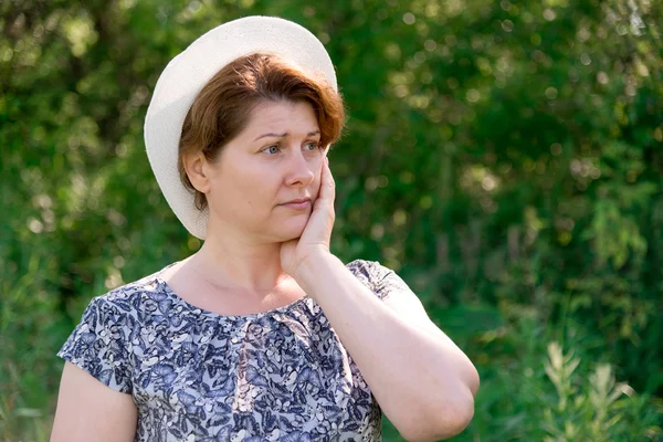 Mujer reflexiva en sombrero de verano en la naturaleza — Foto de Stock