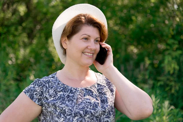 Femme en chapeau parler sur téléphone portable à l'extérieur — Photo