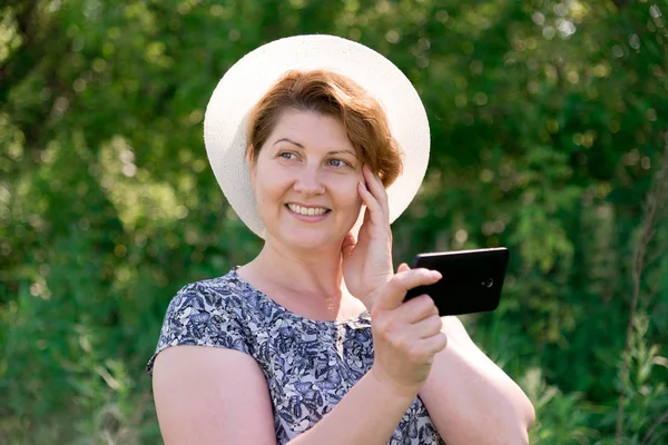 Mujer en sombrero con teléfono celular fuera — Foto de Stock