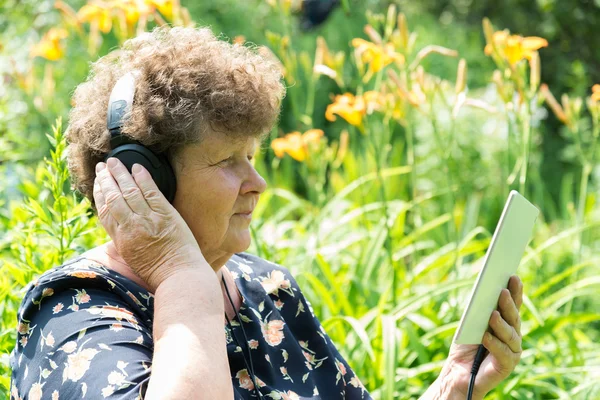 Mulher encaracolada ouvindo música com fones de ouvido e tablet — Fotografia de Stock