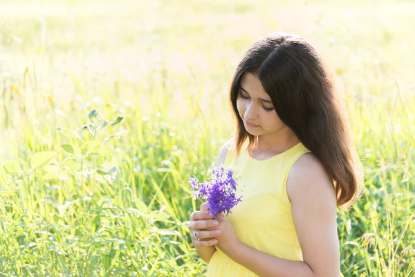 Meisje met boeket van wilde bloemen in de zomer veld — Stockfoto