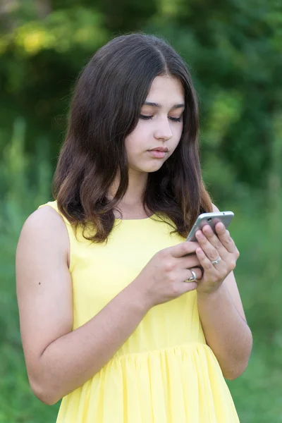 Menina de 14 anos lê sms no telefone — Fotografia de Stock