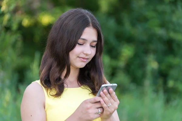 Menina de 14 anos lê sms no telefone — Fotografia de Stock